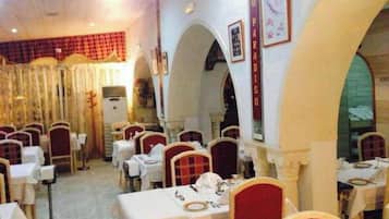 Un restaurante con varias mesas y sillas, una decoración en rojo y blanco y un diseño de interiores clásico.