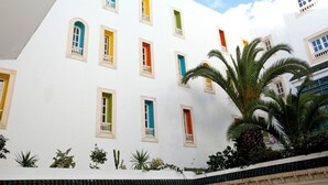 A white building with multiple windows, some with balconies, and a palm tree in the foreground. - Hotel Residence Mahmoud (Hammamet)