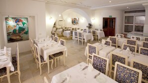 A dining area with multiple tables and chairs, a painting on the wall, and a door labeled 'SORTIE'. - Hotel Residence Mahmoud (Hammamet)