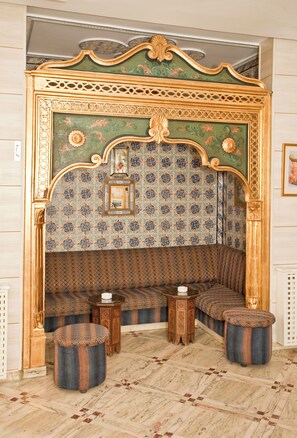 A room with a patterned wall, a sofa, a small table, and two stools. - Hotel Residence Mahmoud (Hammamet)