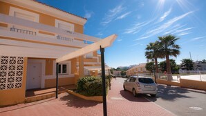 A residential building with a balcony, a car parked in front, and a clear sky. - Villas del Golf TH 23 (Manilva)