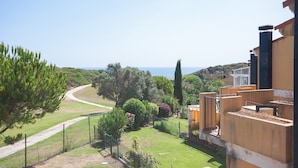 A residential area with a view of the sea, a winding road, and a variety of trees and shrubs. - Villas del Golf TH 23 (Manilva)