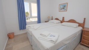 A double bed with white linens, a wooden headboard, a bedside table, a lamp, and a framed picture on the wall. - Villas del Golf TH 23 (Manilva)