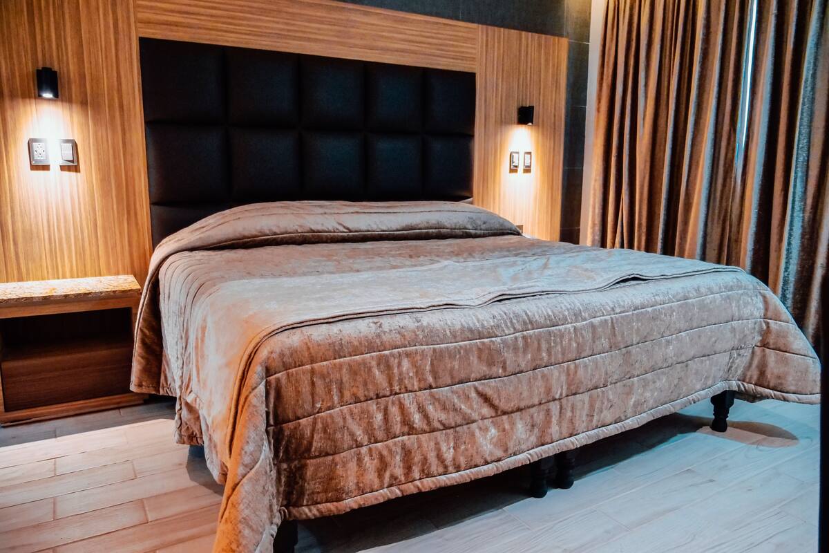 Un dormitorio con una cama grande, cabecera de madera y lámparas de noche.