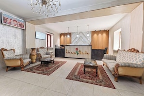 A spacious lobby with a reception desk, two sofas, a coffee table, and a chandelier.