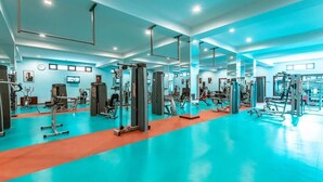 A gym with various exercise machines, mirrors, and a blue and orange floor.