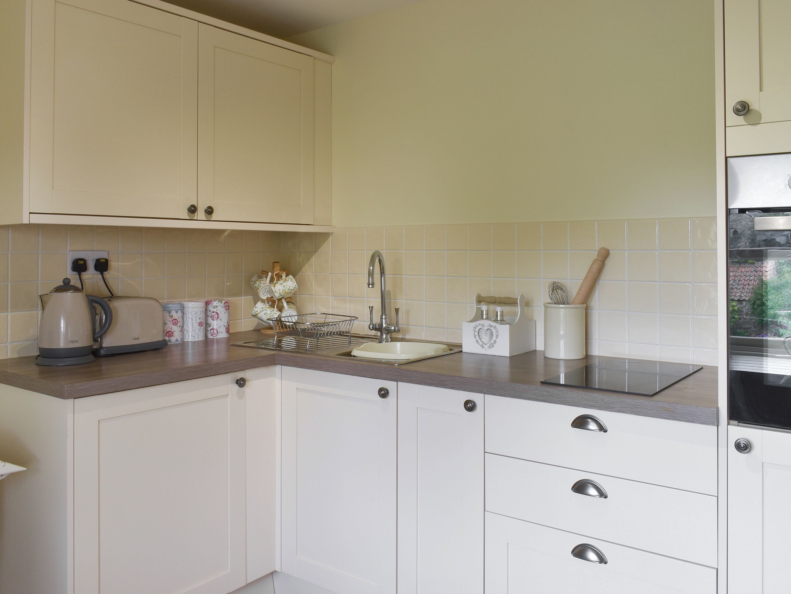A kitchen with white cabinets, a sink, a toaster, and a kettle.