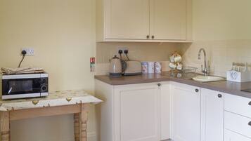 A compact kitchen with a microwave, kettle, and sink.