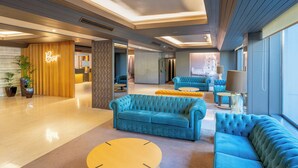 A modern hotel lobby with a bar area, plush blue sofas, and a large window offering a view. - HF Ala Sul (Porto)