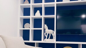 Ein Wohnzimmer mit einem weißen Sofa, einer blauen Akzentwand und einem großen Flachbildfernseher, der an der Wand montiert ist.