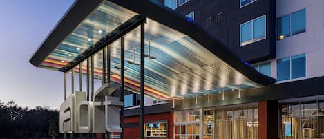 Un hotel moderno con un llamativo letrero que dice 'HOTELS', grandes ventanales y un diseño de techo distintivo.