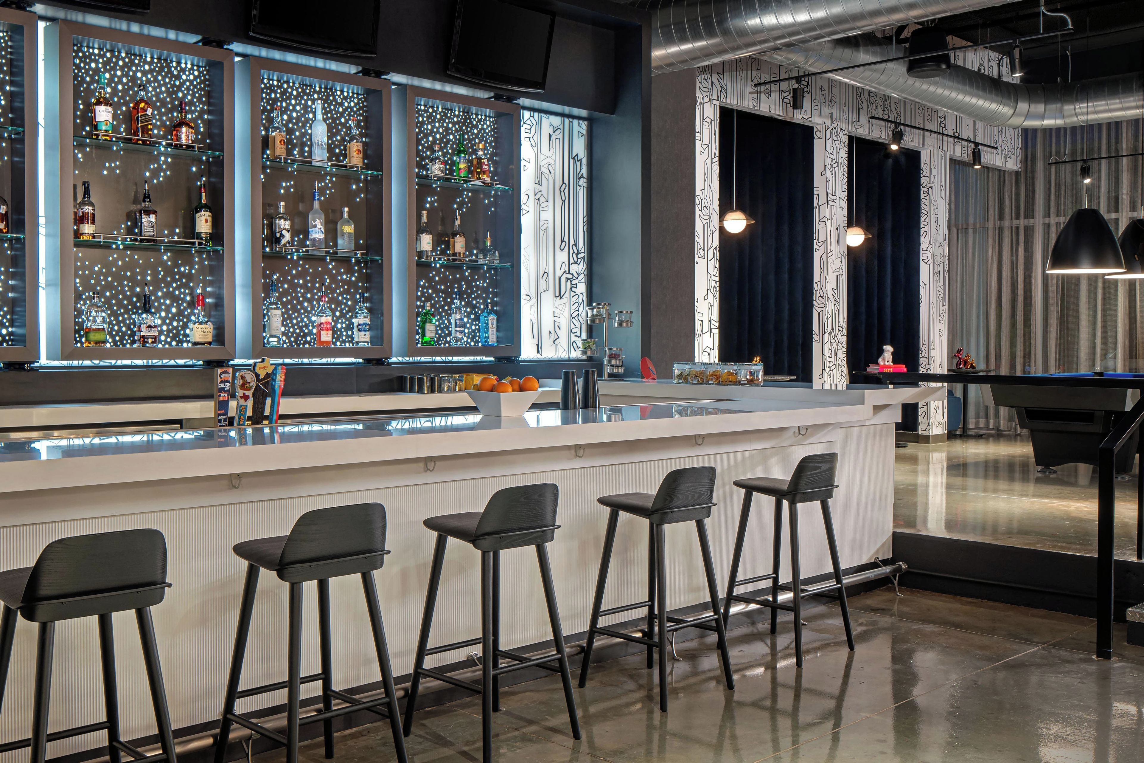 A bar area with a counter, stools, and shelves of bottles.