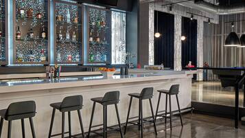A bar area with a counter, stools, and shelves of bottles.