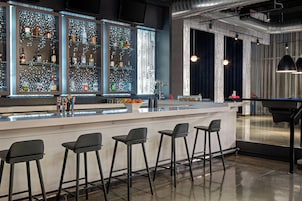 Zona de bar con barra, taburetes y estanterías llenas de botellas.