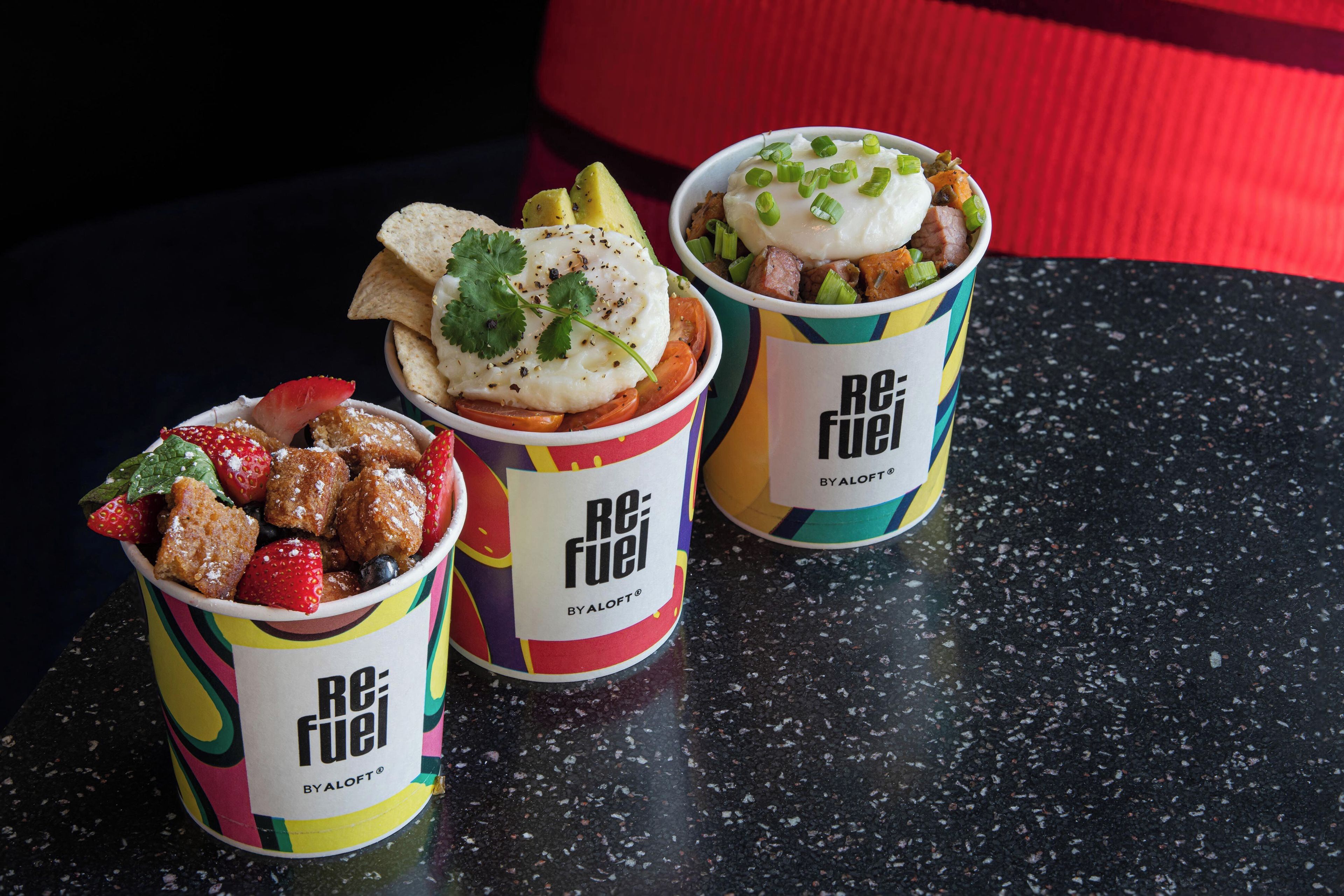 Três recipientes de comida com a marca 'ReFuel' sobre uma bancada preta.