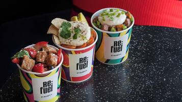 Três recipientes de comida com a marca 'ReFuel' sobre uma bancada preta.