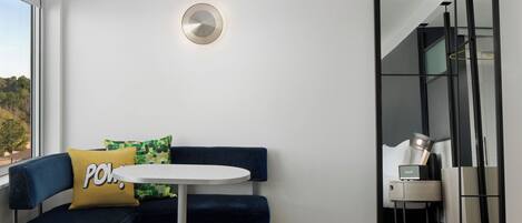 A modern hotel room with a blue sofa, a small round table, and a mirror.
