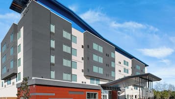 A modern building with multiple floors, large windows, and a covered entrance area.
