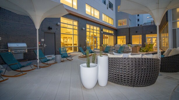 An outdoor patio area with seating, planters, and a grill.