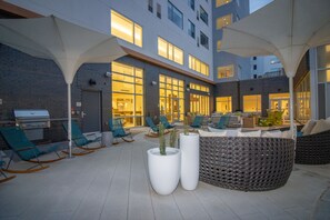 Un patio al aire libre con asientos, macetas y una parrilla.