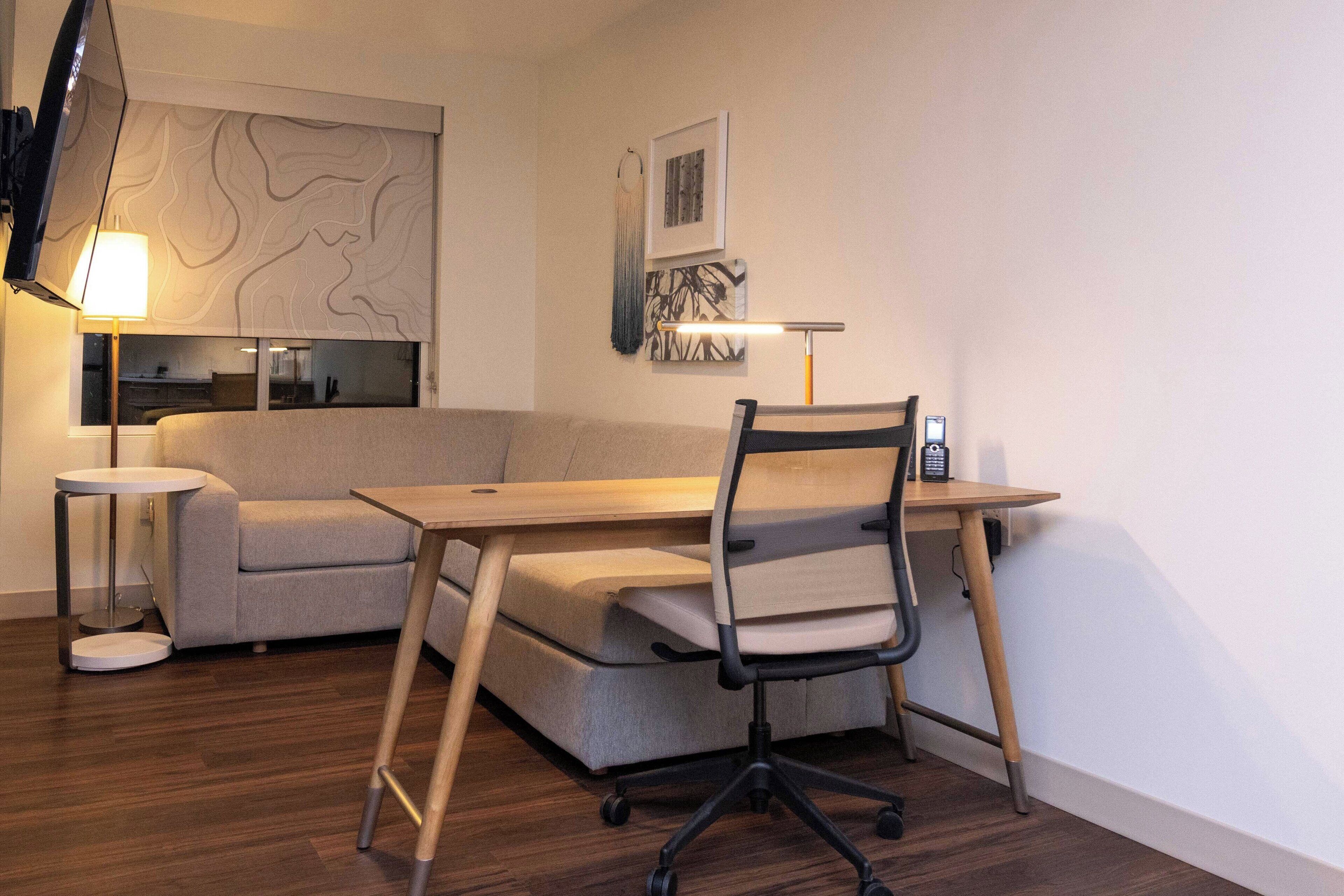Un espace de bureau moderne comprenant un bureau, un fauteuil de bureau et un canapé.