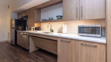 A modern kitchen with wooden cabinets, a stainless steel refrigerator, a microwave, and a dishwasher.