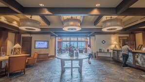 A lobby with a stone floor, wooden furniture, and two large pendant lights.