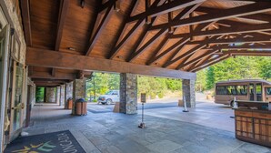 A covered entrance with stone pillars, a reception desk, and a van parked outside.