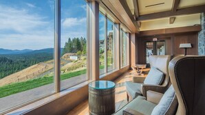 A spacious room with large windows offering a view of a mountainous landscape.