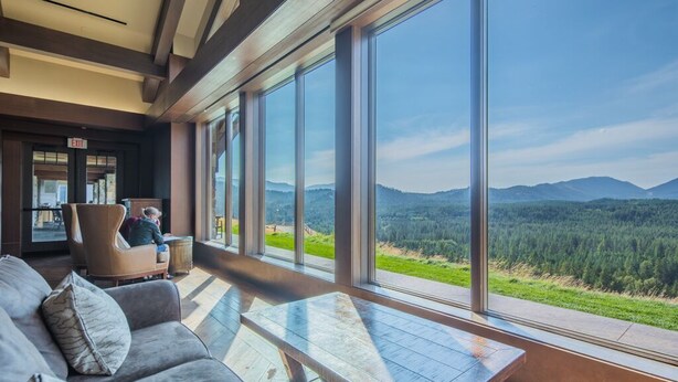 A modern interior with a large window offering a view of a forested mountain range.