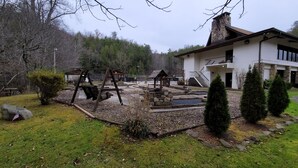 A modern building with a stone facade, a covered patio, and a small pond. - Miss Daisy’s Retreat is a cozy getaway that will comfortably sleep four adults! (Gatlinburg)