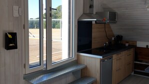 A modern kitchen with a large window, a built-in oven, and a stainless steel dishwasher. - Bel appartement avec terrasse à 5mn de SAINT-CAST (Matignon)