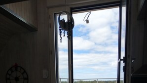 A room with a large window, a metal staircase, and a clock on the wall. - Bel appartement avec terrasse à 5mn de SAINT-CAST (Matignon)