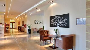 A hotel lobby with a polished floor, a reception desk, and a seating area with modern chairs. - Golden Line (Varna)