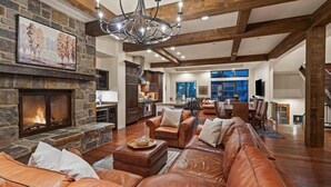 A spacious living area with a stone fireplace, leather sofas, and a dining area with a large window.