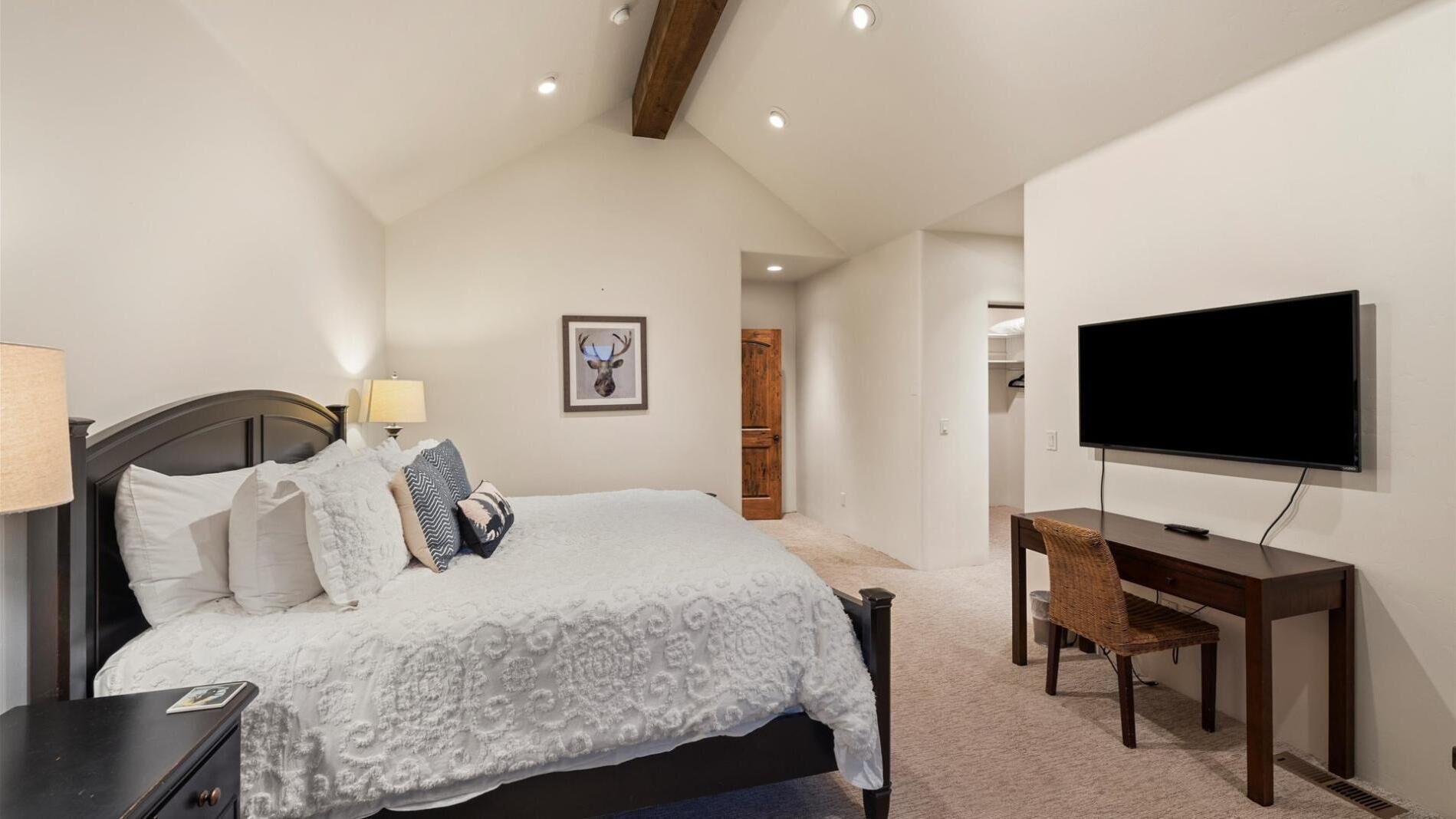 A bedroom with a bed, bedside table, lamp, and a TV on a stand.