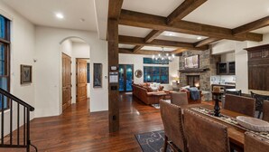 A spacious living room with a fireplace, wooden beams, and a stone wall.