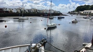 Un puerto con varias embarcaciones amarradas, una superficie acuática tranquila y edificios a lo largo de la orilla.