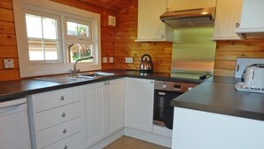 Una cocina con paredes de madera, armarios blancos, una campana extractora de acero inoxidable y un horno empotrado.