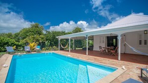 A swimming pool with lounge chairs and a covered patio area.
