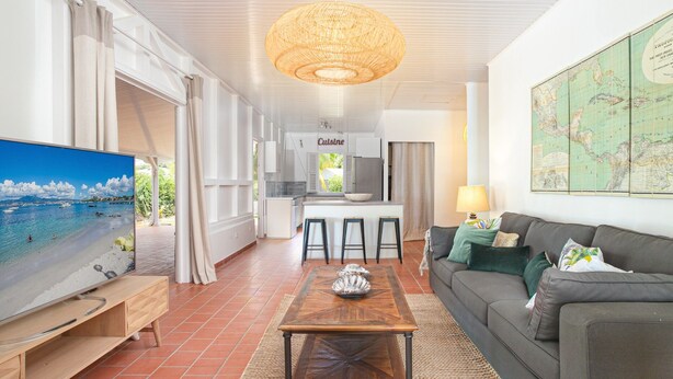 A spacious living area with a large flat-screen TV, a wooden coffee table, a dark sofa, and a map on the wall.