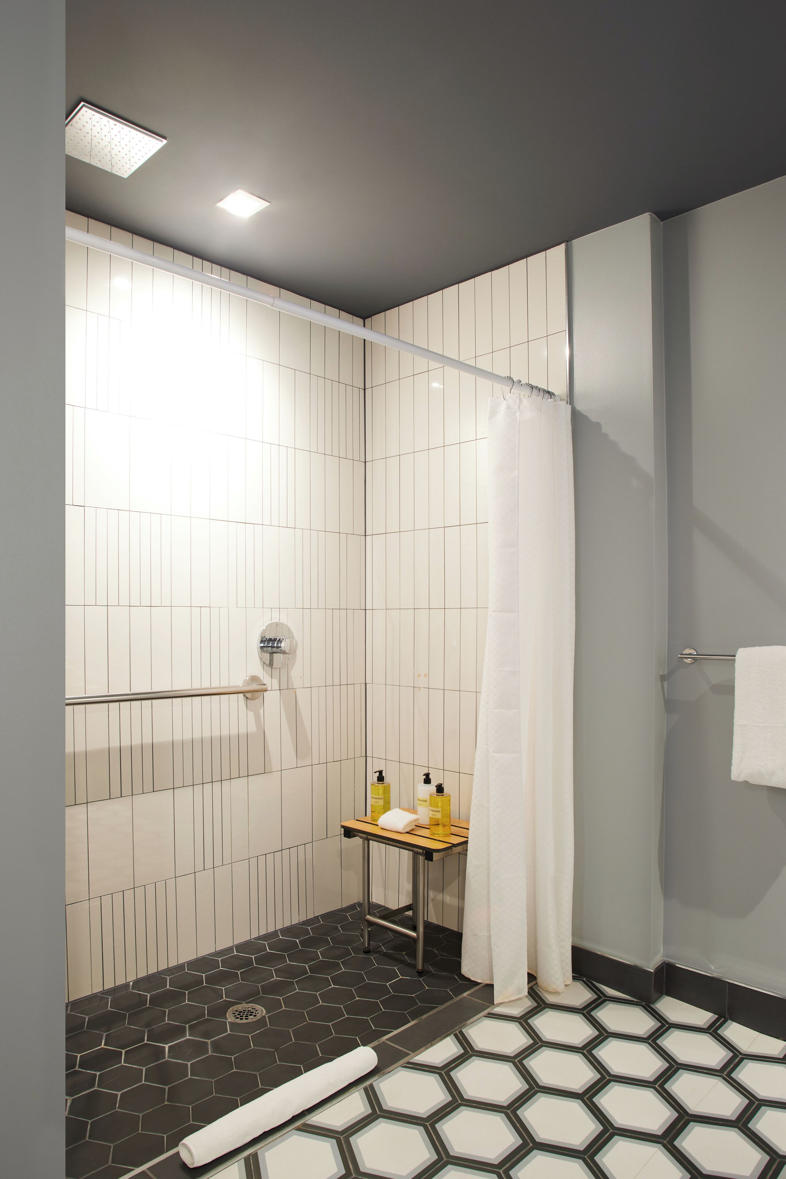 A modern bathroom with a shower, a towel rack, and a small table with toiletries.