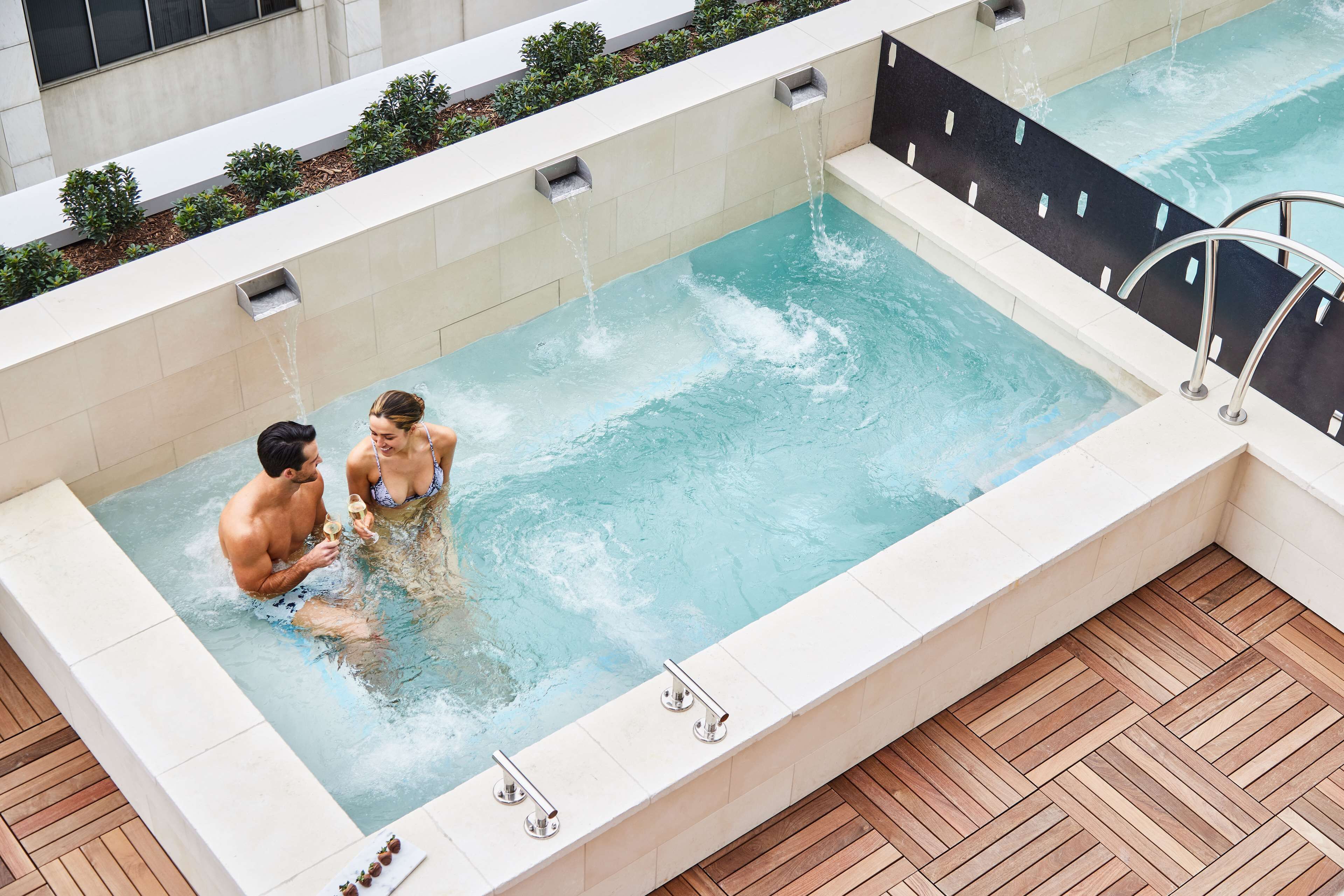 Una bañera de hidromasaje rectangular con un muelle de madera alrededor.
