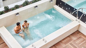 Una bañera de hidromasaje rectangular con un muelle de madera alrededor.