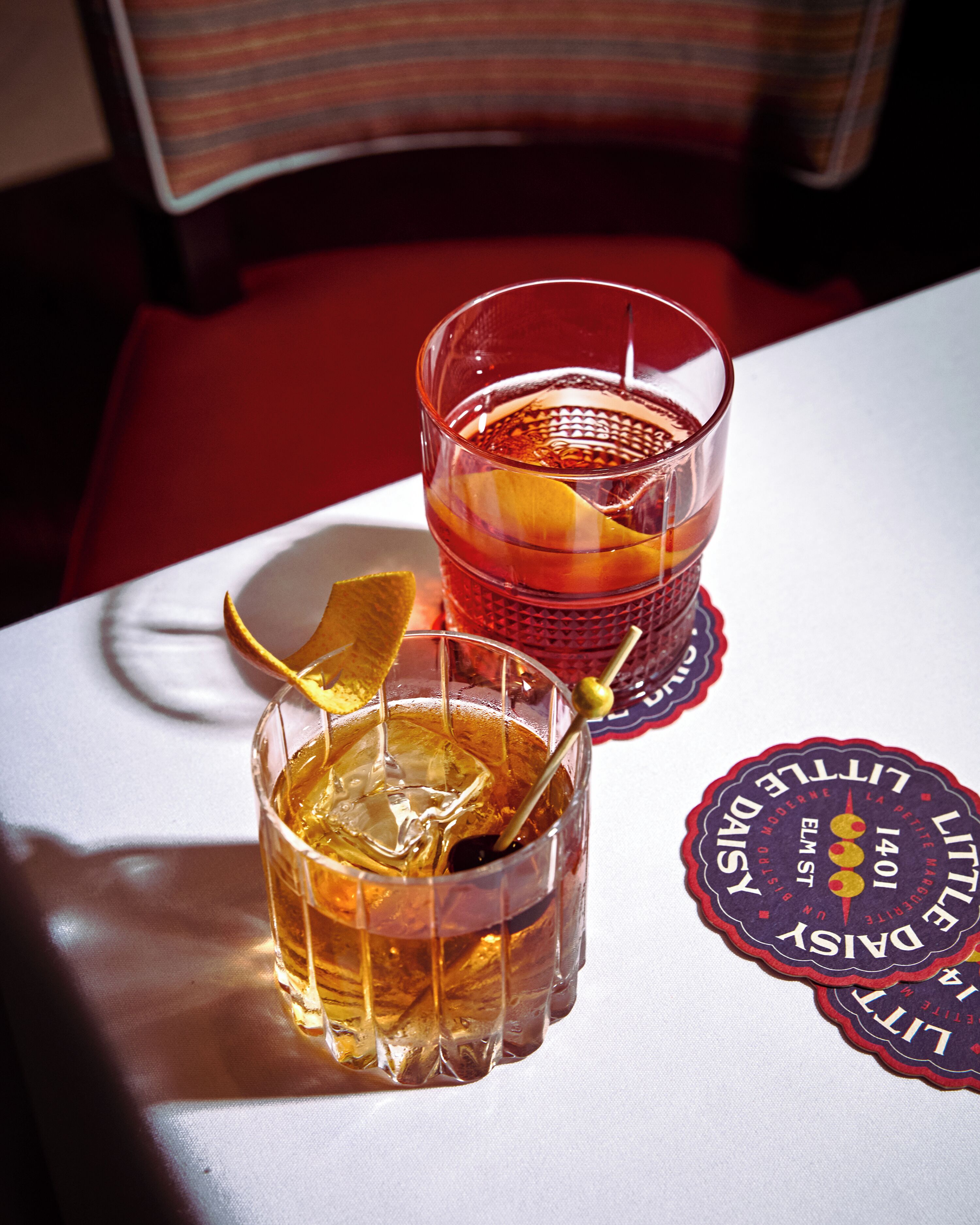 Two glasses of amber-colored beverage on a table with a placemat.