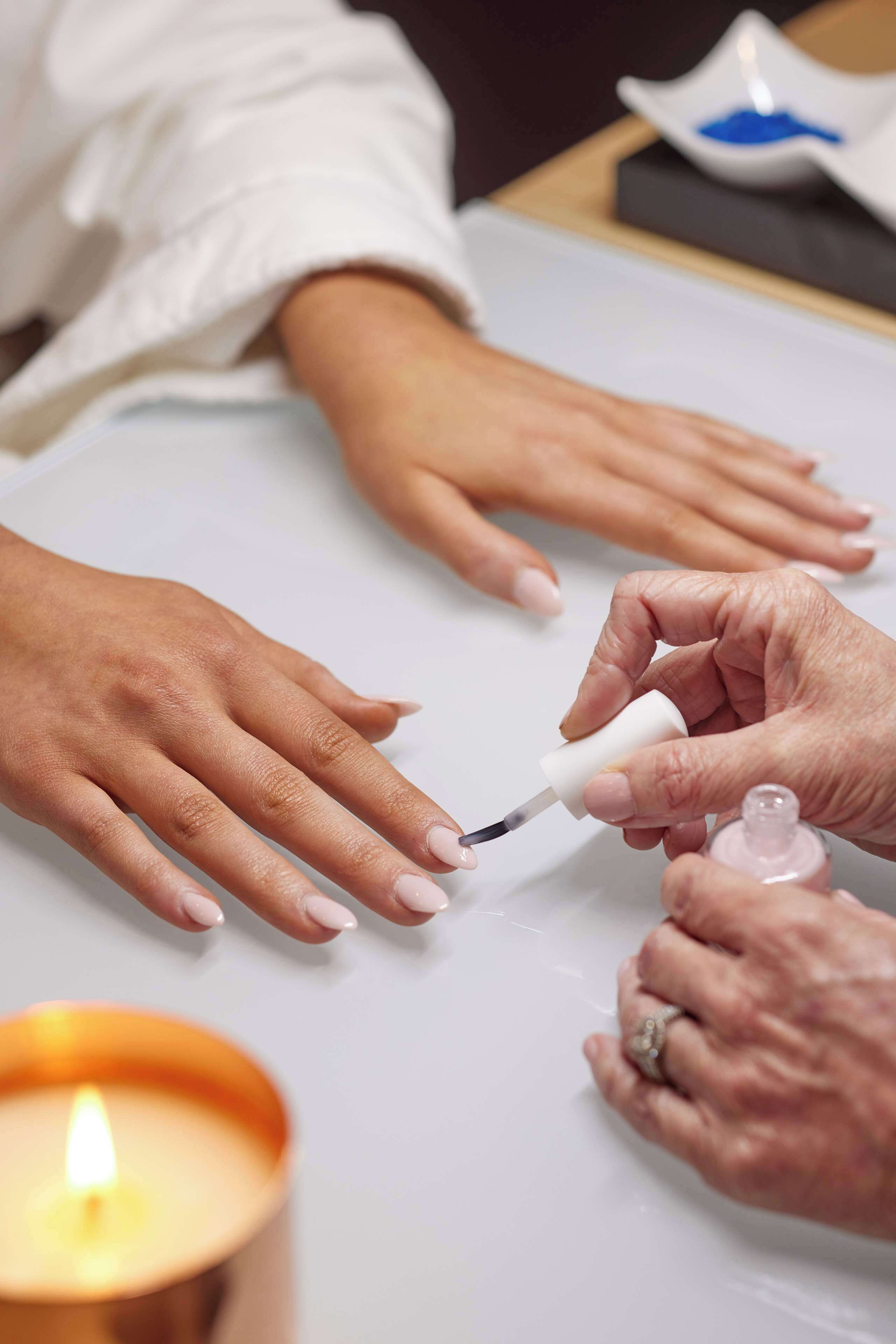 A close-up of hands getting nail polish applied.