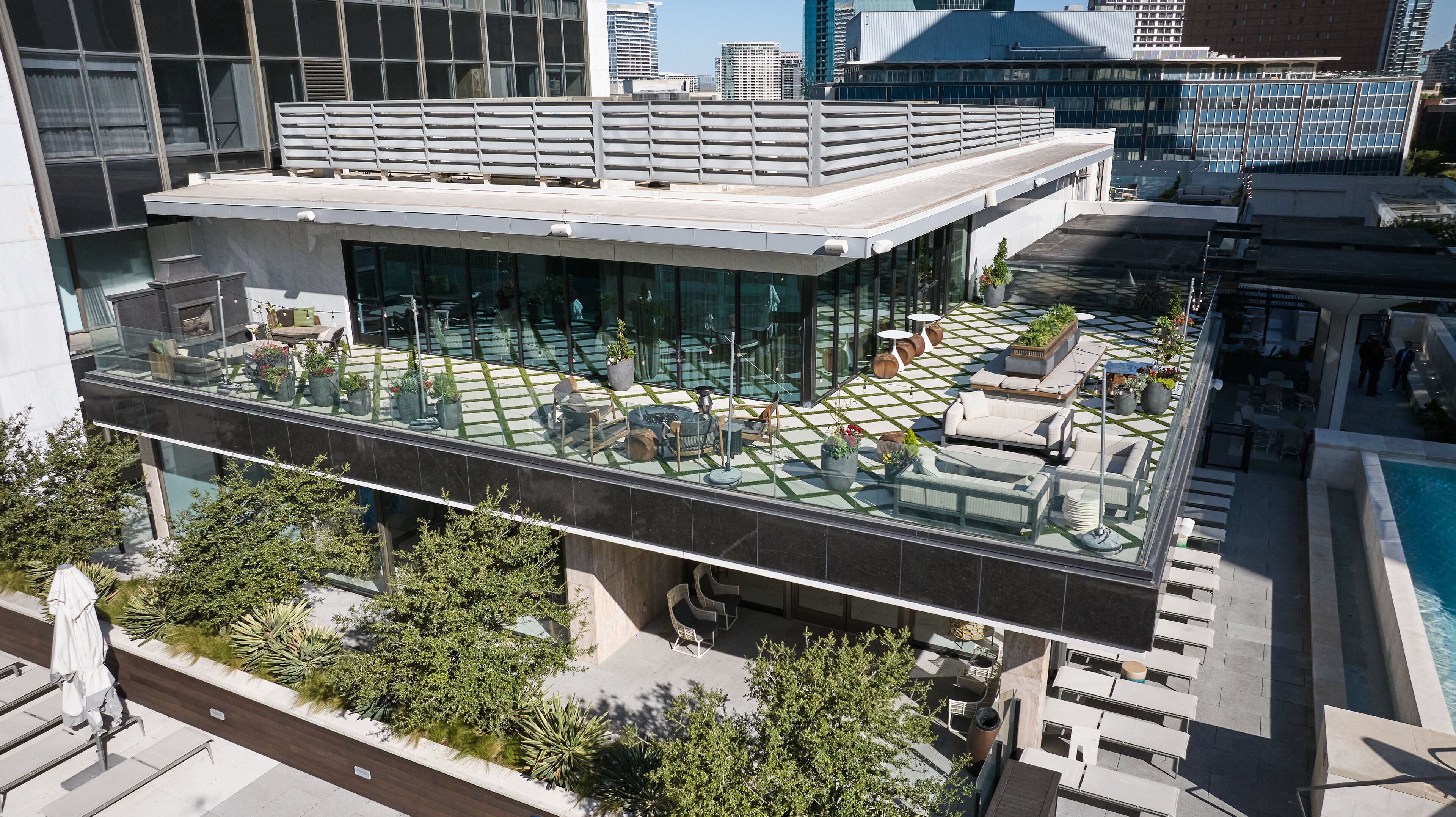 A rooftop terrace with outdoor seating, a pool, and a glass barrier.