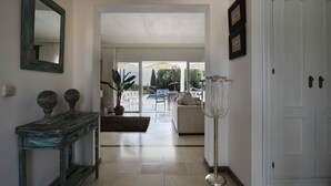 A hallway with a wooden console table, a mirror, and a white door. - Villa Pinsapo (Benahavís)