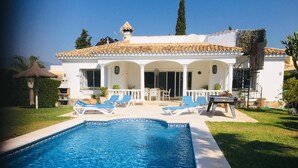 A pool with blue water, surrounded by white walls and a tiled roof. - Villa Pinsapo (Benahavís)