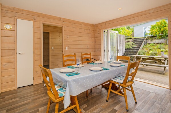 Un interior de madera con una mesa de comedor preparada para cuatro personas, rodeada de sillas de madera.